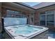 A bubbling hot tub on a stone patio with a brick home exterior and a partially retracted cover at 5268 Courtyard Ln, Belmont, NC 28012