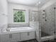 Bright bathroom featuring a soaking tub, a tiled shower with a glass door, and a large window at 631 May Green Dr, Clover, SC 29710