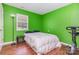 Cozy bedroom with green walls and hardwood floors, featuring a bed and exercise bike at 7224 Newell Acres Dr, Charlotte, NC 28215