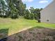 A spacious backyard showcasing lush greenery with a view of the property's exterior at 8516 Paw Valley Ln, Charlotte, NC 28214