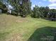 Expansive backyard with green grass, some trees, and a gentle slope at 8516 Paw Valley Ln, Charlotte, NC 28214