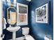 Stylish blue powder room featuring a pedestal sink, gold mirror, and an eye-catching black and white print at 106 N Laurel Ave # 118, Charlotte, NC 28207