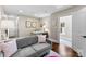 Comfortable living room featuring a gray couch, wood floors, and an adjacent space for work or relaxation at 106 N Laurel Ave # 118, Charlotte, NC 28207