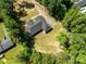 Aerial view shows the home's roof and backyard nestled within a wooded neighborhood at 108 Woodwinds St, Locust, NC 28097