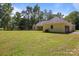 Large backyard with a well-maintained lawn, mature trees, and the back of the house at 108 Woodwinds St, Locust, NC 28097