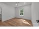 Bright bedroom with wood-look floors, white trim, ceiling fan, and door to walk-in closet at 108 Woodwinds St, Locust, NC 28097