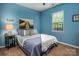 Comfortable bedroom featuring blue walls, a cozy bed, bedside table, and ample natural light from the window at 134 Cherry Bark Dr, Mooresville, NC 28117