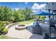 Backyard oasis featuring a fire pit, stone seating, lush landscaping, and an outdoor kitchen at 134 Cherry Bark Dr, Mooresville, NC 28117
