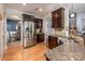 Spacious kitchen featuring stainless steel appliances, granite counters, dark wood cabinetry, and an archway to dining area at 134 Cherry Bark Dr, Mooresville, NC 28117