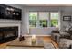 Comfortable living room featuring hardwood floors, a fireplace, and large windows overlooking the backyard at 134 Cherry Bark Dr, Mooresville, NC 28117