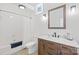 Well-lit bathroom featuring modern vanity with marble countertop, a shower with a tub, and a decorative window at 208 Island View Rd, Mount Holly, NC 28120