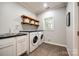 Efficient laundry room equipped with washer, dryer, utility sink and upper shelving at 2984 Starnes Dr, Rock Hill, SC 29730