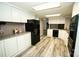 Bright kitchen featuring white cabinets, laminate flooring, and black appliances at 34107 Watson Rd, Albemarle, NC 28001