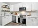 Bright kitchen features stainless steel appliances, marble backsplash, white cabinets, and wood floating shelves at 617 Rock Hill Church Rd, Matthews, NC 28104