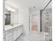 Modern bathroom featuring a double vanity, marble tile floor, and glass-enclosed shower, offering a spa-like experience at 7717 Nautical View Dr, Denver, NC 28037