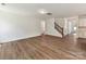 Living room with hardwood floors, white trim, stairs, and open floor plan leading to kitchen at 7717 Nautical View Dr, Denver, NC 28037