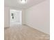 Open-concept living area with neutral carpeting leading into a separate room, bathed in soft natural light at 7717 Nautical View Dr, Denver, NC 28037