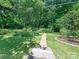 Brick pathway and lush greenery create a serene backyard ambiance with mature trees at 827 Museum Dr, Charlotte, NC 28207