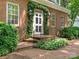 Charming brick home with a white front door framed by climbing ivy and elegant sconces at 827 Museum Dr, Charlotte, NC 28207