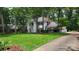Two-story home with a lush front lawn, tall trees, and a long driveway leading to a garage at 9424 Whitethorn Dr, Charlotte, NC 28277