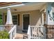 Inviting front porch with white railings, brick accents, and a dark-colored front door and decorative shutters at 110 Leeper Ave, Belmont, NC 28012