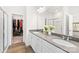 Bright bathroom featuring double sinks, sleek gray countertops, and a glass shower next to a walk-in closet at 13920 Winmau Ln, Huntersville, NC 28078