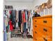 Organized walk-in closet with hanging clothes, shoe racks, storage bins, and a wooden dresser at 13920 Winmau Ln, Huntersville, NC 28078