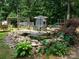 Scenic backyard showcasing a serene pond, playhouse, green slide, and seating under a striped umbrella at 170 Eagle Dr, Salisbury, NC 28144