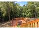Spacious wood deck with custom wood swing in a backyard surrounded by mature trees and black metal fence at 18568 Mainsail Ct, Lancaster, SC 29720