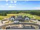 Aerial view of a modern farmhouse-style clubhouse near a golf course with ample parking at 18568 Mainsail Ct, Lancaster, SC 29720