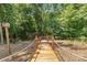Inviting wooden walkway through the trees leads down to a wooded area with a bird house at the start at 18568 Mainsail Ct, Lancaster, SC 29720