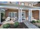 Charming front porch with white columns, comfortable seating and manicured landscaping at 2909 Julian Glen Cir, Waxhaw, NC 28173