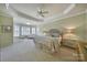 Bright main bedroom offers neutral walls, plush carpet, tray ceiling, ceiling fan, and sitting area by windows at 2909 Julian Glen Cir, Waxhaw, NC 28173