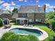 Brick home's rear exterior with a screen porch overlooking a pool area with chairs and lush landscaping at 2909 Julian Glen Cir, Waxhaw, NC 28173