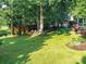 Lush backyard featuring a well-manicured lawn, mature trees, and a cozy outdoor seating area at 3401 Cresta Ct, Charlotte, NC 28269