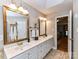 Bathroom featuring a double sink vanity, framed mirrors, and a doorway to the bedroom at 3401 Cresta Ct, Charlotte, NC 28269