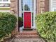 Inviting red front door with brick steps and lush greenery enhances the home's entry at 3401 Cresta Ct, Charlotte, NC 28269