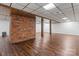 Finished basement with brick accent wall, overhead wood beams, and hardwood flooring at 3943 Peggy Ln, Mint Hill, NC 28227