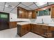 Basement kitchenette with wood cabinetry, white counters, stainless sink, and tile flooring at 3943 Peggy Ln, Mint Hill, NC 28227