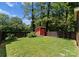 Backyard featuring lush grass, mature trees, a wooden fence, and a small storage shed at 423 Solomon St, Charlotte, NC 28216