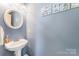 Stylish powder room featuring blue walls, a pedestal sink, updated fixtures, and decorative artwork at 4462 Kellybrook Dr, Concord, NC 28025