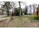 Overgrown backyard with shed, picnic table, mature trees, and a green lawn at 4601 Mendham Dr, Charlotte, NC 28215
