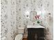 Stylish powder room features floral wallpaper, a marble countertop, and charming fixtures at 9000 Whirlaway Ln, Waxhaw, NC 28173