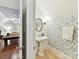 Stylish powder room with pedestal sink, decorative mirror, and patterned wallpaper, adjacent to the billiard room at 9000 Whirlaway Ln, Waxhaw, NC 28173