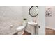 Stylish powder room featuring patterned wallpaper, a round mirror, and a pedestal sink at 9311 Dunwich Dr, Gastonia, NC 28056