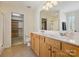 Bathroom featuring double sinks, wood cabinets, and views of the walk in closet and shower at 10409 Dominion Village Dr, Charlotte, NC 28269