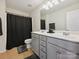 Bathroom featuring double vanity with gray cabinets, framed mirror, and shower with a black curtain at 10409 Dominion Village Dr, Charlotte, NC 28269