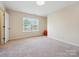 Well-lit bedroom with neutral walls, carpet, and a window providing natural light at 10409 Dominion Village Dr, Charlotte, NC 28269