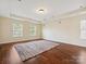 Large bedroom showcasing hardwood floors, tray ceiling, and ample natural light through windows at 10409 Dominion Village Dr, Charlotte, NC 28269
