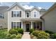 Inviting front porch with black door, bright red chairs, and lush landscaping at 12341 Mcallister Park Dr, Charlotte, NC 28277